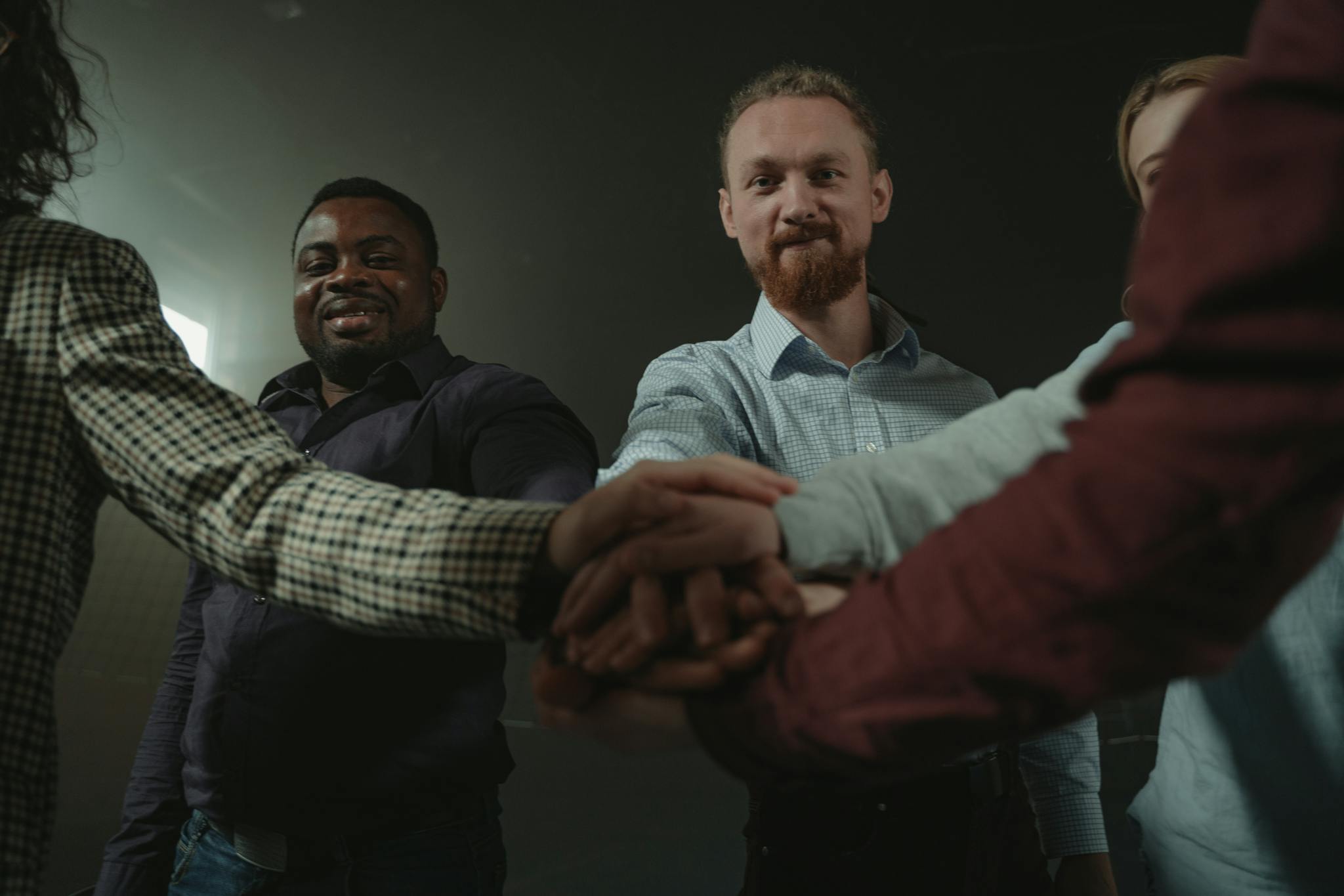 Diverse group of adults forming a team huddle, symbolizing unity and collaboration.