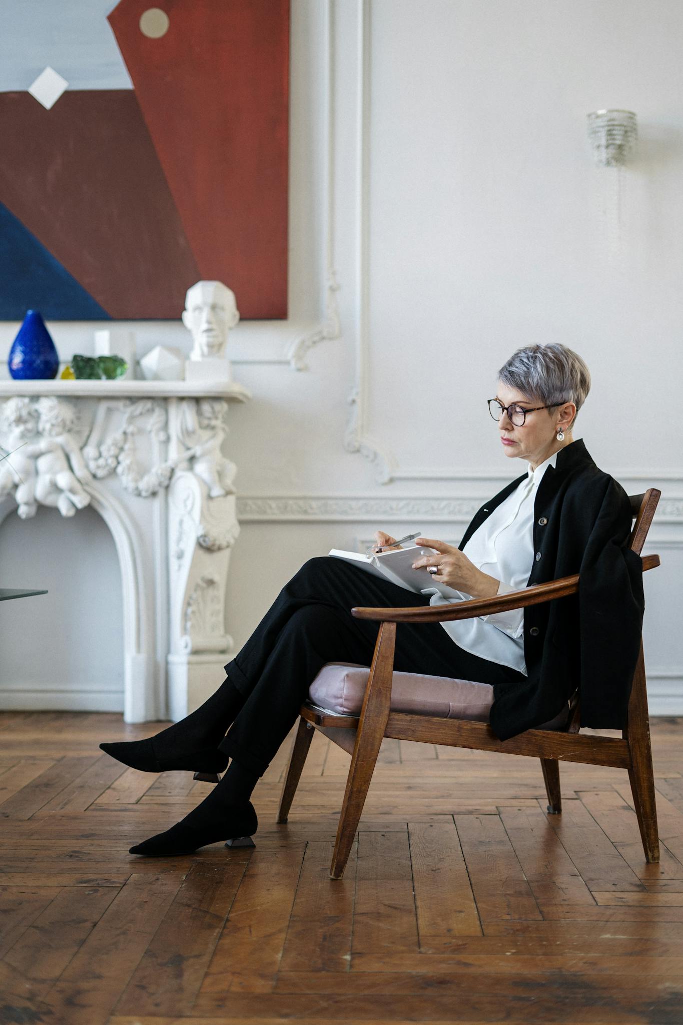 Woman with glasses reads in stylish office, offering a sense of professionalism and focus.